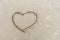 Symbol of heart written by hand on sand of beach