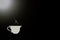 Symbol of hot coffee in a white cup on a black background and a white highlight