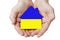 The symbol of the house in children`s hands in the colors of the flag of Ukraine. The concept of a home, a family hearth,