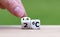 Symbol for limiting global warming. Hand turns a dice and changes the expression `2Â°C` to `1.5Â°C`, or vice versa.