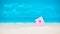 Symbol of little lilac house on the sand with bright cloudy blue painted sky background