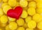 Symbol of love family red heart cloth on a background of candied yellow candy balls sweet. base postcard valentine