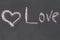Symbol of love heart inscription message Love`s contrasting black background is drawn chalk