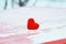the symbol of love scarlet heart on a wooden table under the snow in the Park