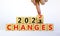 Symbol of planning 2022 changes new year. Businessman turns a wooden cube and changes words `Changes 2021` to `Changes 2022`.