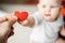 The symbol of a red heart in the hand of a man transmitting it to a child in a small hand