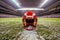 A symbolic scene of a lone football helmet resting on the 50-yard line of a large stadium, stands empty in the background,