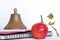 Symbols for education, red delicious homegrown apple, brass school bell stacked on black spiral bound sketch notebook, red folder