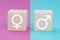 Symbols for feminine and masculine on wooden cubes, pink and blue colored background