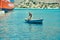 Symi, Greece- July 05 2017: Mature man in shabby vessel raises anchor in the sea near a huge ferry