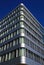 Symmetrical low angle view on modern building edge with silver shiny reflecting facade against deep blue cloudless sky