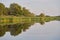 Symmetrical reflection trees, grass, sky in pond