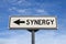 Synergy road sign, arrow on blue sky background