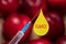 Syringe with chemical injection close-up. Blurred peaches in the background. The concept of GMO foods, vegetables and