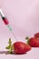 Syringe injecting artificial coloring into a fresh strawberry.