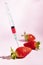 Syringe injecting artificial coloring into a fresh strawberry.