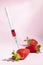 Syringe injecting artificial coloring into a fresh strawberry.