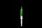 Syringe for injection with green liquid on a black background.