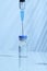 Syringe inserted into a vaccine bottle to draw liquid medicine, cool toned image, blue color temperature