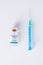 Syringe leaning on a vaccine bottle with COVID-19 sign on white  background. Global pandemic and healthcare concept.