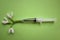 A syringe lies on a green background. Fresh white snowdrops come out of the syringe