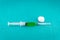 Syringe with medicine and cotton on green background