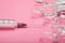 Syringe with a needle and ampoules on a pink background