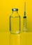 Syringe with a needle and medicine in a bottle on a yellow background