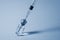 Syringe needle pierces the cap of medical vial. Monochrome photo.