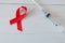 Syringe and red ribbon on light wooden background. World AIDS Day