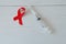 Syringe and red ribbon on light wooden background. World AIDS Day