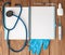 Syringe, stethoscope, blank page notepad, pill and gloves on the doctor table. Medical diagnosis or doctor prescription mockup