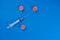 Syringe and three simulated virus on blue background