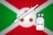 Syringe and vaccine vial on blur background with Burundi flag