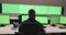 System security specialist working at system control center. Room is full of green screens, chroma screen and security