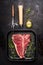 T-bone Steak on frying grill pan with meat fork, oil and seasoning on dark rustic background