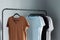 T-shirts of neutral colors on  hanger against  gray wall