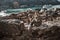 Tabby cat lies on a stone wall above a port city with orange roofs. Portraits with pets.