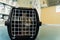 Tabby cat sitting in a cage on the floor of a veterinary clinic waiting on his appointment with the veterinarian looking anxious