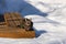 Tabby cat sitting on a deck bench surrounded with snow