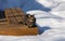 Tabby cat sitting on a deck bench surrounded with snow