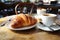 A table adorned with a flaky croissant and steaming coffee