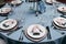 Table appointments. Table setting with empty plates, forks, glasses and knives and light blue tableclothes. Served table in restau