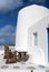 Table and bench in yard of Mykonos, Greece. House on mountain landscape, architecture. Building with whitewashed walls