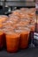 Table with black tablecloth with many clear plastic cups with tops containing an orange smoothie type drink.