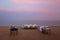 A table and chairs for a barbecue party on the beach, at sunset, and a calm sea in the background