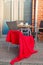 Table and chairs with red blanket outdoors in street cafe