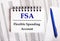 On the table are charts and reports, on which lie a blue pen and a notebook with the word FSA Flexible Spending Account