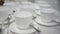 On the table are clean white saucers, spoons, coffee cups. white ceramic tea cups on a clean table. Table with dishes in