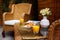 A table in the courtyard is served for Breakfast. There is orange juice, pastries, and jam on a wicker table